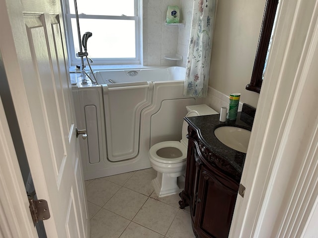 bathroom with toilet, vanity, a tub to relax in, and tile patterned floors