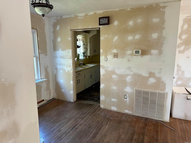 spare room with a textured ceiling, dark wood-type flooring, and sink