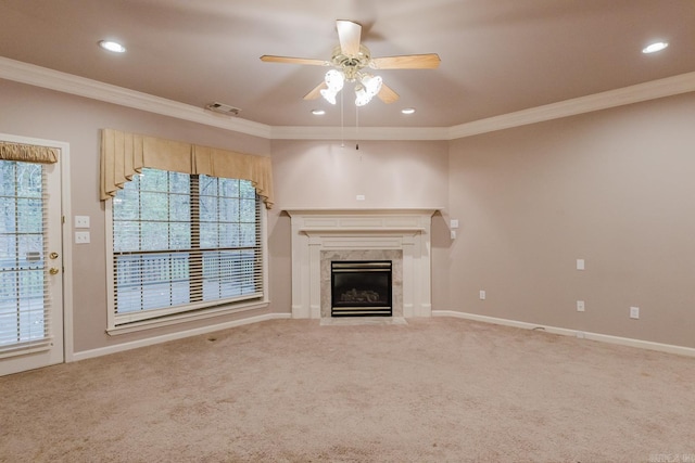 unfurnished living room featuring carpet flooring, crown molding, ceiling fan, and a premium fireplace