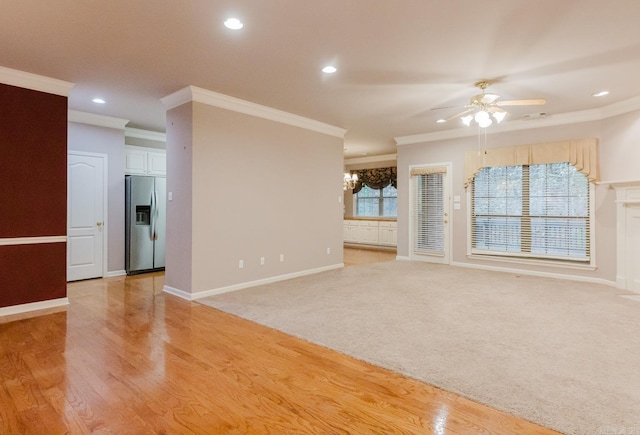 unfurnished living room featuring light hardwood / wood-style flooring, ceiling fan with notable chandelier, and ornamental molding