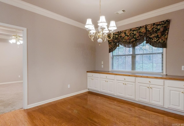 unfurnished dining area featuring ornamental molding, ceiling fan with notable chandelier, and light wood-type flooring