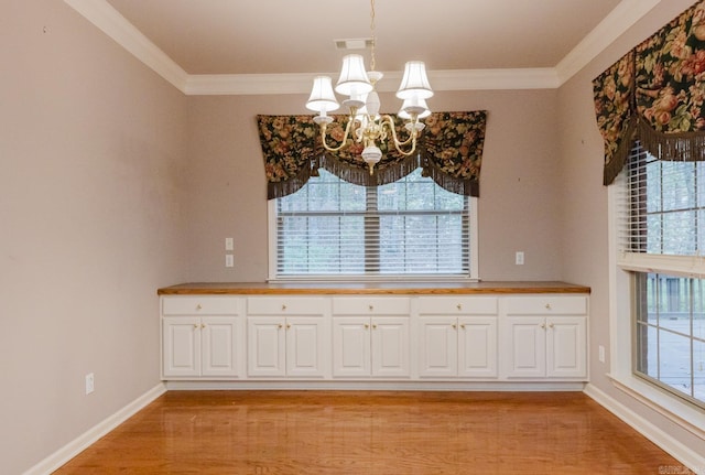 unfurnished dining area with light hardwood / wood-style floors, a wealth of natural light, ornamental molding, and a notable chandelier