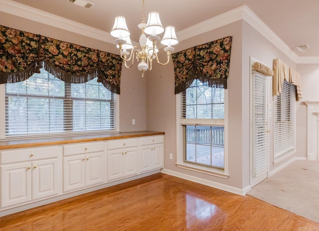 unfurnished dining area featuring a notable chandelier, light wood-type flooring, and crown molding