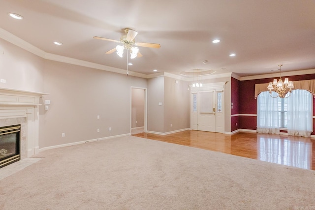 unfurnished living room with ceiling fan with notable chandelier, light hardwood / wood-style floors, crown molding, and a high end fireplace