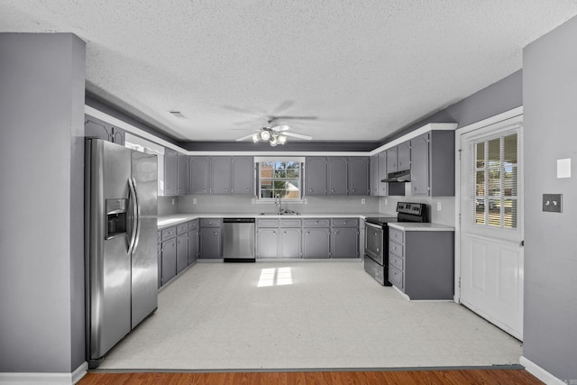 kitchen with gray cabinetry, sink, ceiling fan, light hardwood / wood-style floors, and stainless steel appliances