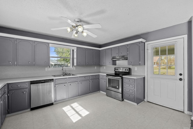 kitchen featuring gray cabinetry, ceiling fan, sink, stainless steel appliances, and a textured ceiling