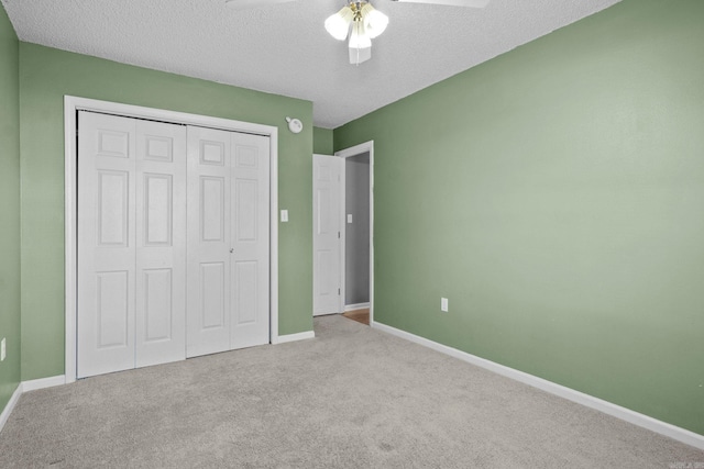 unfurnished bedroom featuring ceiling fan, a closet, light colored carpet, and a textured ceiling