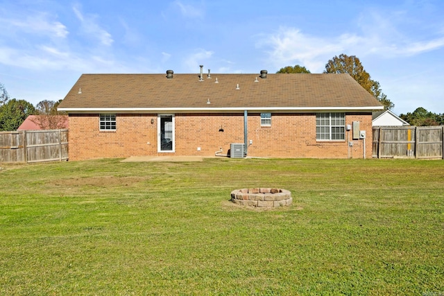 back of house with a yard, central AC unit, and a fire pit