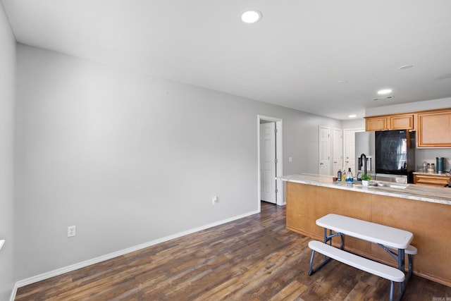 kitchen with kitchen peninsula, black refrigerator with ice dispenser, dark hardwood / wood-style flooring, and sink