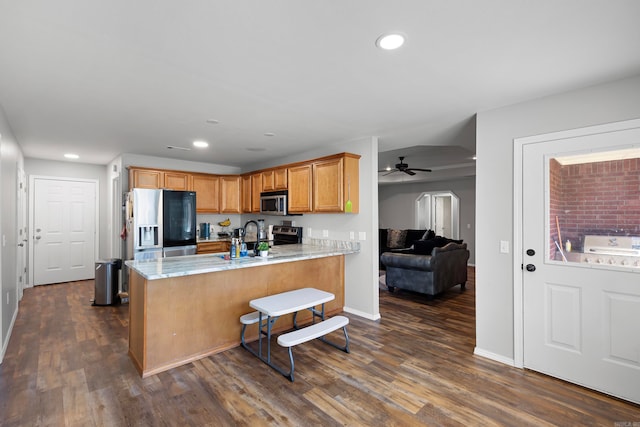 kitchen featuring kitchen peninsula, appliances with stainless steel finishes, ceiling fan, and dark wood-type flooring