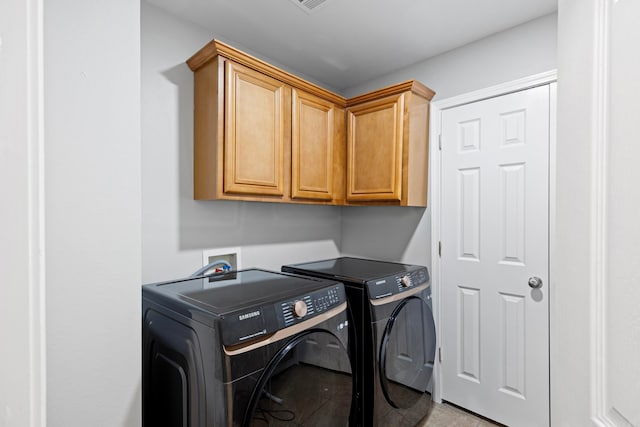 laundry area with washing machine and clothes dryer and cabinets