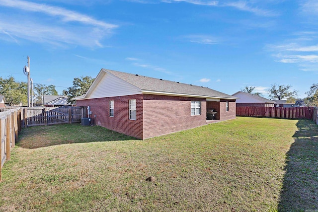 rear view of house with central AC unit and a yard