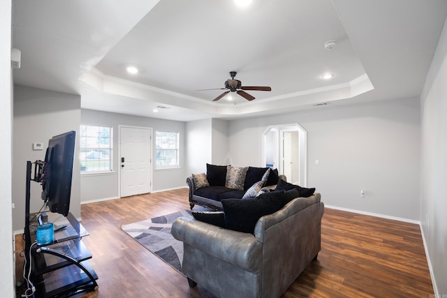 living room featuring a tray ceiling, ceiling fan, and dark wood-type flooring