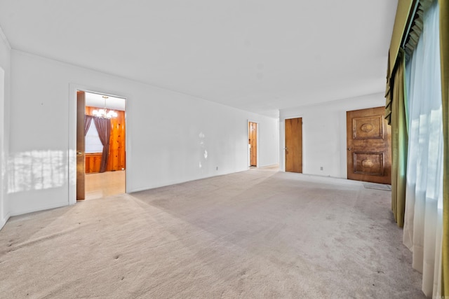 spare room with a chandelier and light colored carpet