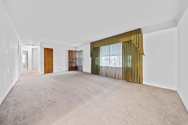 spare room with ornamental molding and light carpet