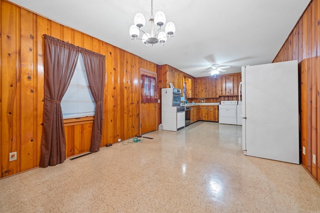 kitchen with wood walls, white fridge, washer and dryer, and decorative light fixtures