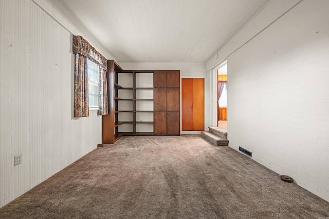 interior space featuring light colored carpet and brick wall