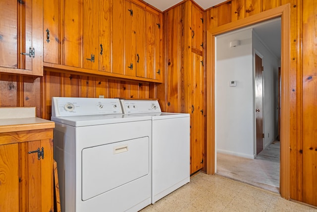 washroom with wood walls, cabinets, and independent washer and dryer