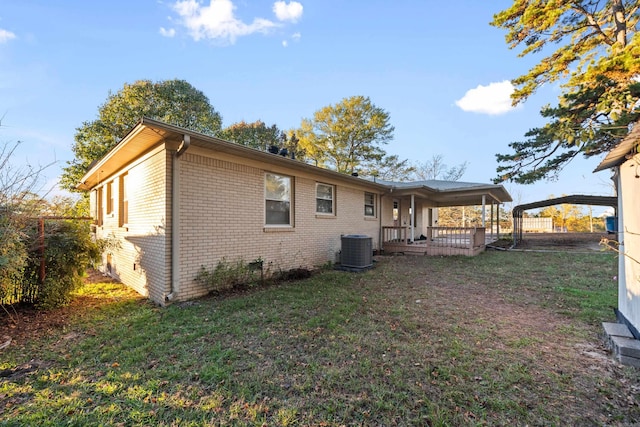 back of property featuring central air condition unit, a carport, and a lawn