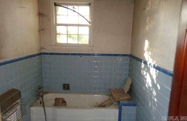 bathroom featuring tile walls and a bathing tub