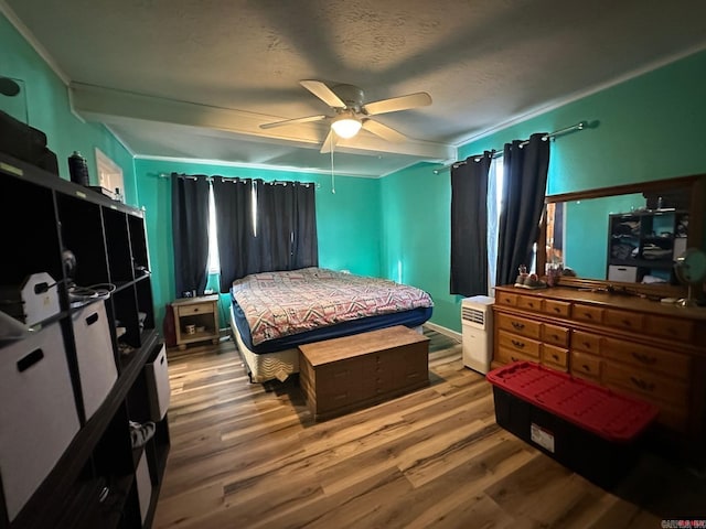 bedroom with ceiling fan, hardwood / wood-style floors, crown molding, and a textured ceiling