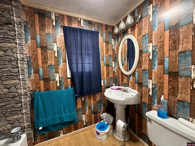 bathroom with wood walls, hardwood / wood-style floors, a textured ceiling, and toilet