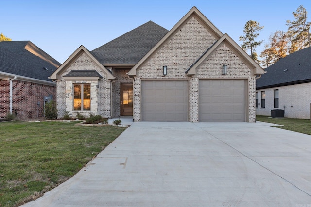 view of front of property featuring central AC unit, a front yard, and a garage