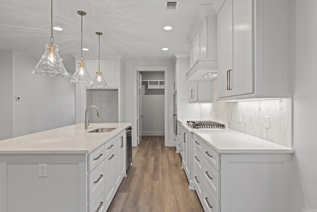 kitchen featuring a kitchen island with sink, white cabinetry, sink, and pendant lighting