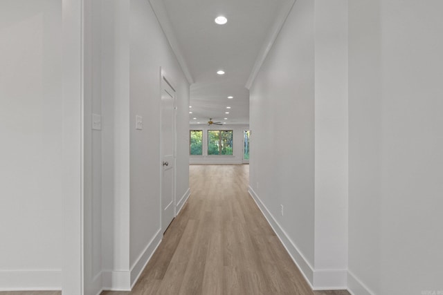 corridor with light hardwood / wood-style floors and ornamental molding