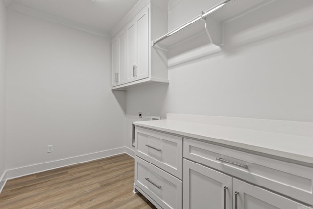 laundry room with crown molding, cabinets, wood-type flooring, and hookup for an electric dryer