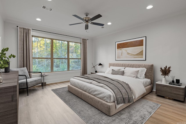 bedroom featuring light hardwood / wood-style flooring, ceiling fan, and crown molding