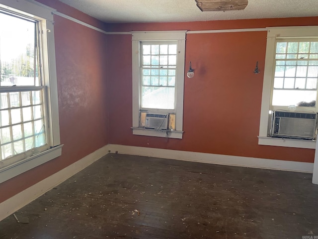 unfurnished room featuring a textured ceiling, plenty of natural light, and cooling unit