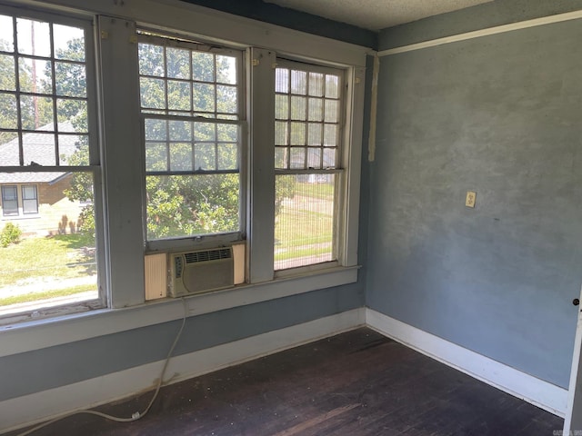 empty room with dark hardwood / wood-style flooring, cooling unit, and a healthy amount of sunlight