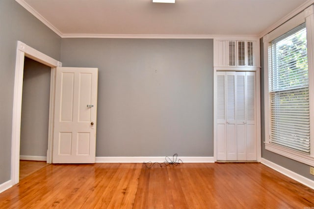 unfurnished bedroom with wood-type flooring, a closet, and ornamental molding