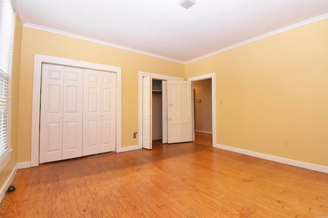 unfurnished bedroom with hardwood / wood-style floors, two closets, and crown molding