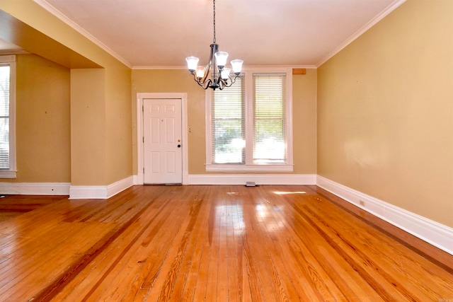 unfurnished dining area with a notable chandelier, wood-type flooring, and crown molding