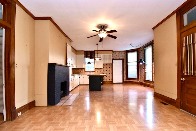 kitchen with white cabinets, decorative backsplash, decorative light fixtures, a kitchen island, and light parquet flooring