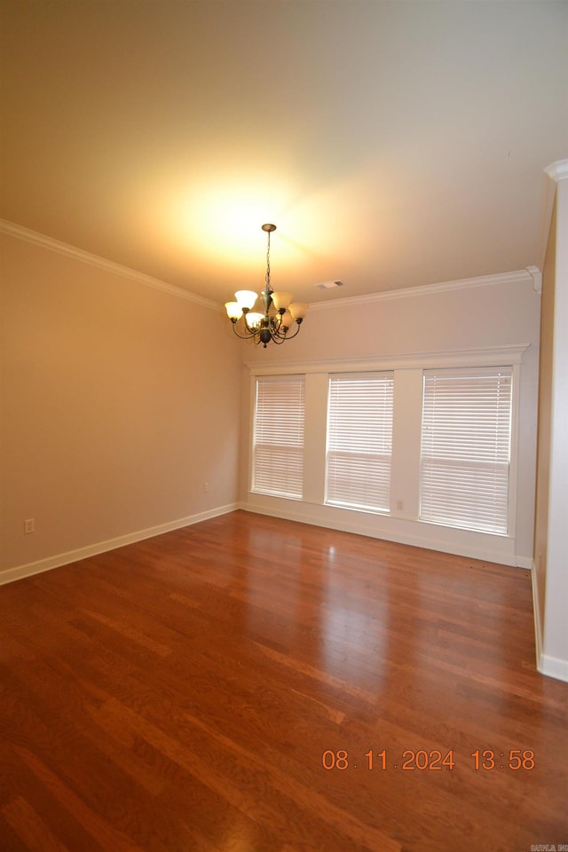 spare room featuring dark hardwood / wood-style flooring, an inviting chandelier, and crown molding