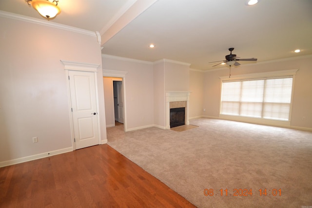 unfurnished living room with hardwood / wood-style flooring, ceiling fan, crown molding, and a tile fireplace