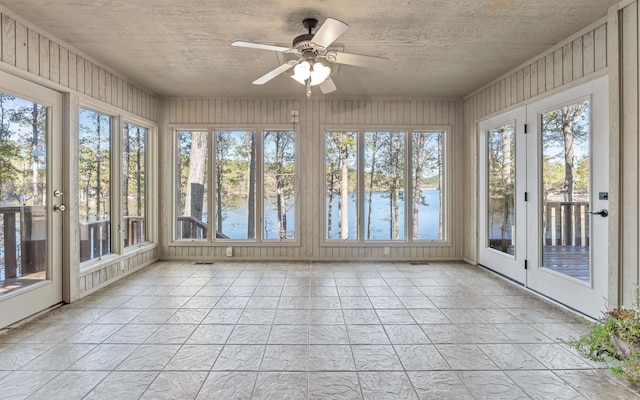 unfurnished sunroom with plenty of natural light, ceiling fan, and a water view