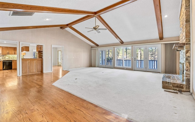 unfurnished living room with beam ceiling, ceiling fan, light hardwood / wood-style floors, and a textured ceiling