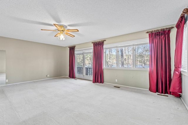 spare room featuring ceiling fan, light colored carpet, and a textured ceiling