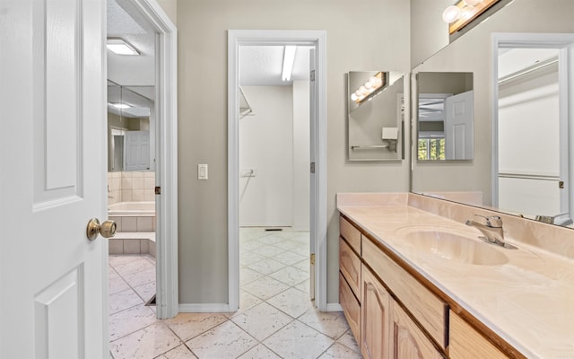 bathroom with tile patterned flooring, vanity, and a relaxing tiled tub