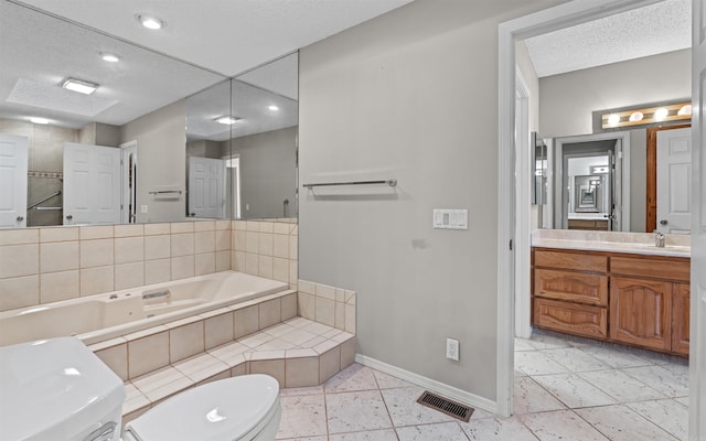 bathroom featuring a bathing tub, tile patterned flooring, a textured ceiling, toilet, and vanity