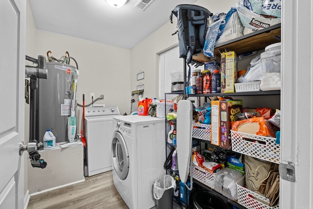 laundry room featuring washing machine and dryer, light wood-type flooring, and water heater