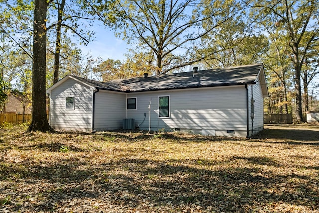 rear view of house featuring central air condition unit and a yard