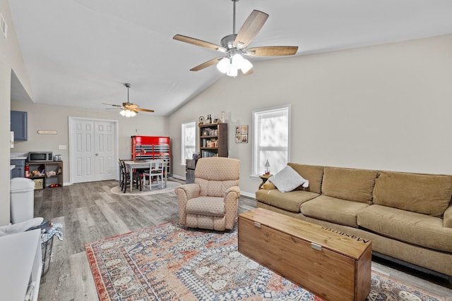 living room with ceiling fan, wood-type flooring, and lofted ceiling