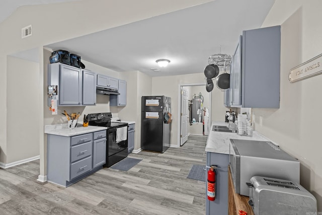 kitchen featuring light hardwood / wood-style floors, vaulted ceiling, gray cabinetry, and black appliances