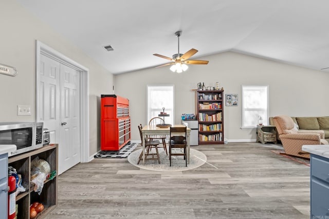 dining room with ceiling fan, light wood-type flooring, and lofted ceiling