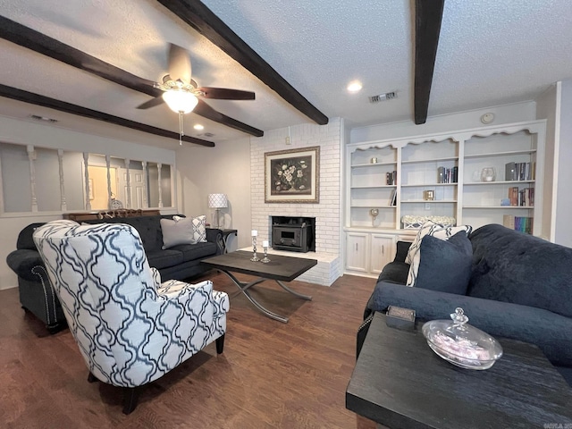 living room with beam ceiling, ceiling fan, a brick fireplace, dark hardwood / wood-style flooring, and a textured ceiling